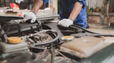 Tamirci, merkezden tamir için gelen bir arabanın motorunu inceliyor. Profesyonel motor uzmanı, araba tamiri, araba arızası. Araba bakım ve onarım konsepti.