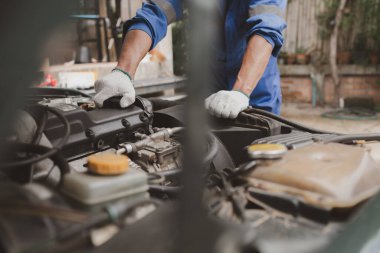 Tamirci, merkezden tamir için gelen bir arabanın motorunu inceliyor. Profesyonel motor uzmanı, araba tamiri, araba arızası. Araba bakım ve onarım konsepti.