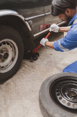 Tamirci lastikleri inceliyor ve uzun çalışma saatleri boyunca eski lastikleri değiştiriyor. Araba tamirleri, araba arızaları, patlak lastikler. Araba lastiği bakımı ve araba tamiri kavramı.