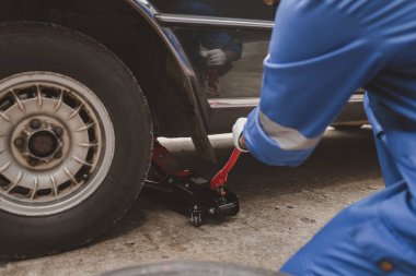 Tamirci lastikleri inceliyor ve uzun çalışma saatleri boyunca eski lastikleri değiştiriyor. Araba tamirleri, araba arızaları, patlak lastikler. Araba lastiği bakımı ve araba tamiri kavramı.