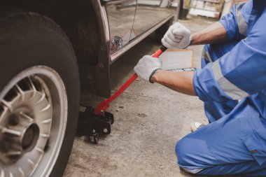 Tamirci lastikleri inceliyor ve uzun çalışma saatleri boyunca eski lastikleri değiştiriyor. Araba tamirleri, araba arızaları, patlak lastikler. Araba lastiği bakımı ve araba tamiri kavramı.