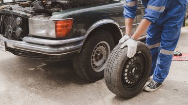 Tamirci lastikleri inceliyor ve uzun çalışma saatleri boyunca eski lastikleri değiştiriyor. Araba tamirleri, araba arızaları, patlak lastikler. Araba lastiği bakımı ve araba tamiri kavramı.