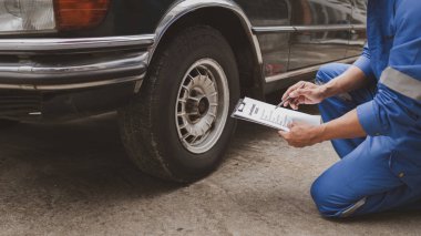 Tamirci lastikleri inceliyor ve uzun çalışma saatleri boyunca eski lastikleri değiştiriyor. Araba tamirleri, araba arızaları, patlak lastikler. Araba lastiği bakımı ve araba tamiri kavramı.