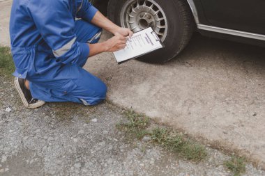 Tamirci lastikleri inceliyor ve uzun çalışma saatleri boyunca eski lastikleri değiştiriyor. Araba tamirleri, araba arızaları, patlak lastikler. Araba lastiği bakımı ve araba tamiri kavramı.