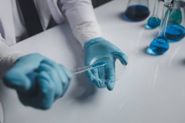 Lab assistant, a medical scientist, a chemistry researcher holds a glass tube through the blood sample, does a chemical experiment and examines a patient's blood sample. Medicine and research concept.