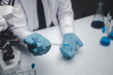 Lab assistant, a medical scientist, a chemistry researcher holds a glass tube through the blood sample, does a chemical experiment and examines a patient's blood sample. Medicine and research concept.