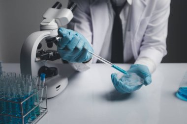 Lab assistant, a medical scientist, a chemistry researcher holds a glass tube through the blood sample, does a chemical experiment and examines a patient's blood sample. Medicine and research concept.