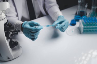 Lab assistant, a medical scientist, a chemistry researcher holds a glass tube through the blood sample, does a chemical experiment and examines a patient's blood sample. Medicine and research concept.