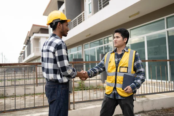 Architect and engineer shaking hands at job site, the project commissioned by the client, and the custom design before delivery. Interior design and decoration ideas.