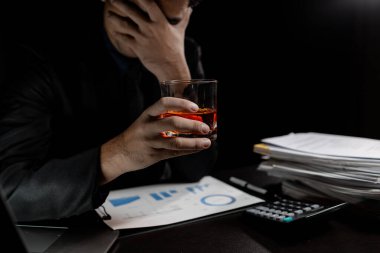 Bir adam viski içer, bir işadamı ağır bir işi bitirdikten sonra ofiste oturup viski içmenin stresinden kurtulur, sarhoş bir adam. Alkol içme konsepti.