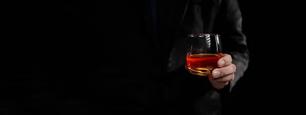 A man drinks whiskey, a businessman relieves stress from work sitting and drinking whiskey in the office after finishing a hard job, a drunk man. Alcohol drinking concept.