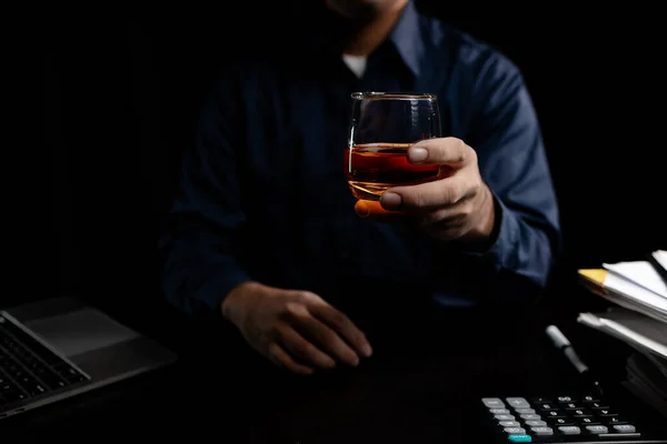 A man drinks whiskey, a businessman relieves stress from work sitting and drinking whiskey in the office after finishing a hard job, a drunk man. Alcohol drinking concept.