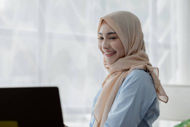 Ofiste tesettürlü bir kadın şirket çalışanı, mali durumların doğruluğu ve güvenliğini sağlamak için şirketin hesaplarını ve mali durumunu denetliyor. Finans ve muhasebe alanında çalışma kavramları.