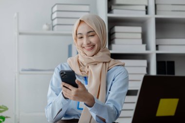 Ofiste tesettürlü bir kadın şirket çalışanı, mali durumların doğruluğu ve güvenliğini sağlamak için şirketin hesaplarını ve mali durumunu denetliyor. Finans ve muhasebe alanında çalışma kavramları.