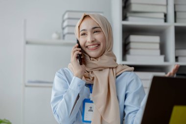 Ofiste tesettürlü bir kadın şirket çalışanı, mali durumların doğruluğu ve güvenliğini sağlamak için şirketin hesaplarını ve mali durumunu denetliyor. Finans ve muhasebe alanında çalışma kavramları.
