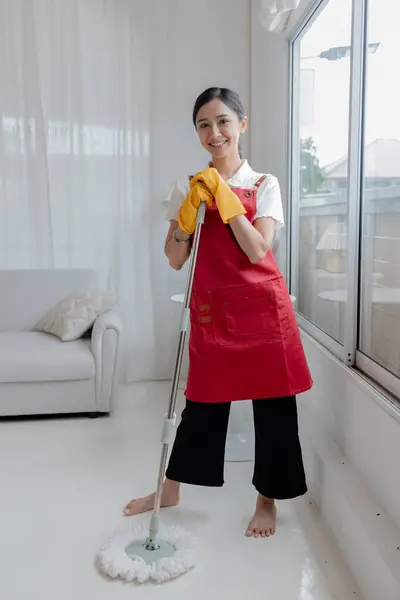 Asian woman cleaning the floor with mop, housekeeper cleaning the company office, maintaining cleanliness in office. Cleaning concept and housekeeper taking care of cleanliness and order in the office