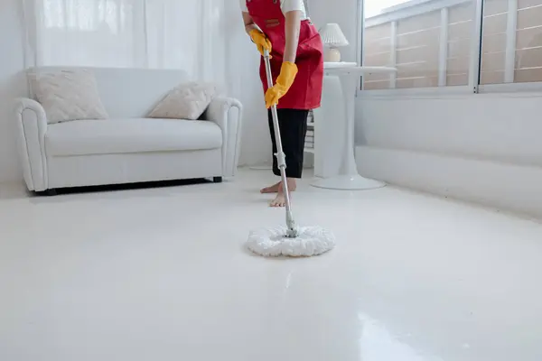 Asian woman cleaning the floor with mop, housekeeper cleaning the company office, maintaining cleanliness in office. Cleaning concept and housekeeper taking care of cleanliness and order in the office