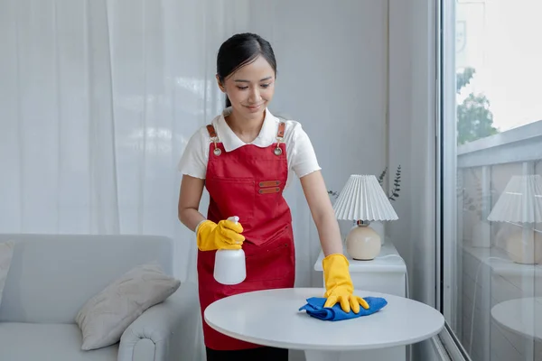 Asian woman cleaning staff, housekeeper cleaning tables in a company office, maintaining cleanliness in the office. Cleaning concept and housekeeper taking care of cleanliness and order in the office.
