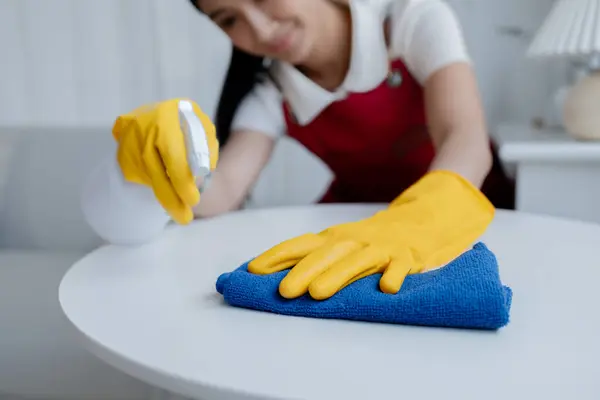 Asian woman cleaning staff, housekeeper cleaning tables in a company office, maintaining cleanliness in the office. Cleaning concept and housekeeper taking care of cleanliness and order in the office.