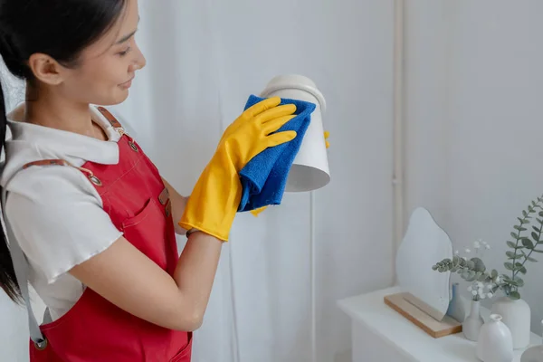 Female cleaning staff, housekeeper cleaning the lamps in the company office, maintaining cleanliness in the office. Cleaning concept and housekeeper taking care of cleanliness and order in the office.