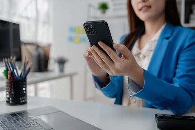 Genç Asyalı iş kadını telefon çeviriyor, finans sektöründe çalışan bir iş kadını, bir şirket için finans planlaması ve mali durumları gözden geçiriyor. Mali yönetim kavramları.