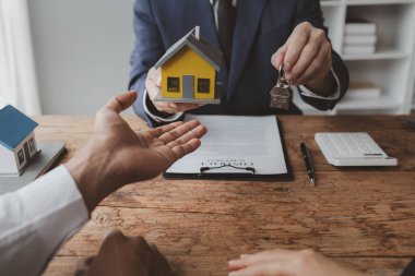 Projede gayrimenkul ve ev satışları düzenleniyor. Birkaç kez gidip bir satıcıyla ev almayı tartışmışlar. Konut projesi satıcısı ev alıp satmanın detaylarını açıklıyor.