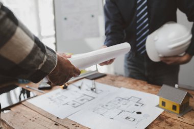 The home design architects are reviewing the house plan draft, the project commissioned by the client, and the custom design before delivery. Interior design and decoration ideas.