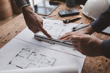 The home design architects are reviewing the house plan draft, the project commissioned by the client, and the custom design before delivery. Interior design and decoration ideas.