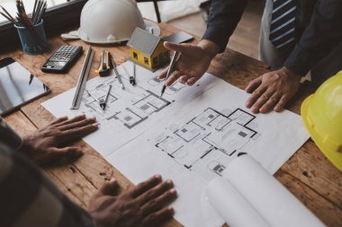 The home design architects are reviewing the house plan draft, the project commissioned by the client, and the custom design before delivery. Interior design and decoration ideas.