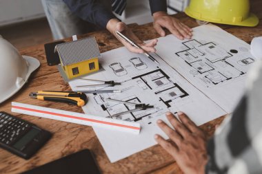 The home design architects are reviewing the house plan draft, the project commissioned by the client, and the custom design before delivery. Interior design and decoration ideas.