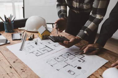 The home design architects are reviewing the house plan draft, the project commissioned by the client, and the custom design before delivery. Interior design and decoration ideas.