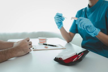 Adam diş hekiminde dişçi muayenesinden geçiyor, profesyonel bir dişçiden diş muayenesi yaptırıyor ve oral bakım tavsiyesi alıyor. Diş tedavisi görme kavramı.