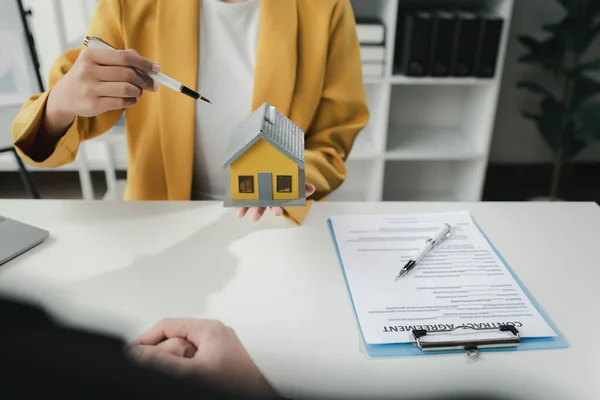 Sales staff discuss home details with customers before agreeing to sign a sales contract, buying and selling real estate, making recommendations and offerings, drafting home sales contracts.