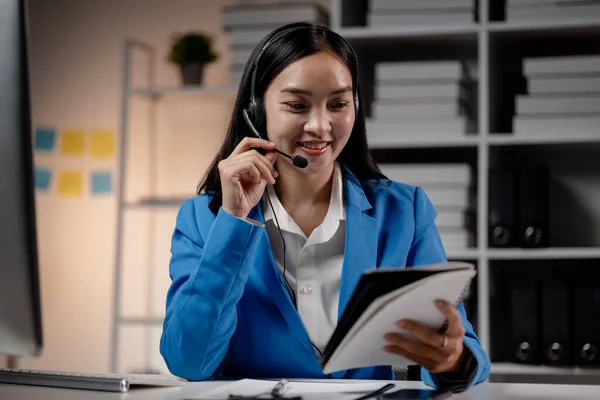 Asian woman wearing headphones and talking to customers. Call center employees answer the phone to help and answer questions from customers who call to use the service. Call center concept.