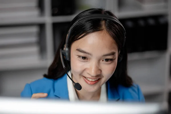 Asian woman wearing headphones and talking to customers. Call center employees answer the phone to help and answer questions from customers who call to use the service. Call center concept.