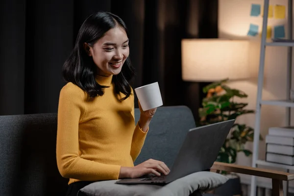Asian woman relaxing on sofa in house, businesswoman spends her vacation watching movies, listening to music and surfing social media on smartphone, texting and chatting with friends. Weekend concept.