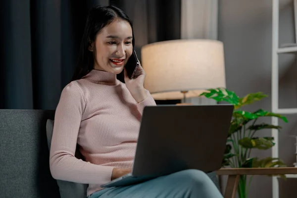 Asian woman in the living room and talking on the phone with friends, female company employee on vacation, spending vacation time and free time relaxing at home, weekend vacation doing activities.