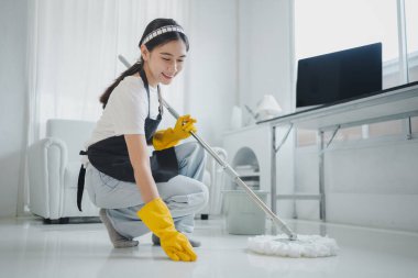 Temizlik ekibi temiz mi değil mi diye zemini kontrol ediyor. Lastik eldiven ve önlük takın ve mutlu bir gülümsemeyle çalışın. Temizlik kimyasalları ve temizlik fikriyle çalışın..