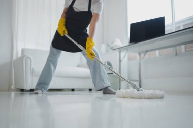 Evdeki yerleri silen temizlik görevlileri temizlik kimyasallarından korunmak için önlük ve lastik eldiven takın. Yerleri temizlemek için paspas kullan. Mikrop temizleme fikirlerini önlemek için evi temiz tutun..