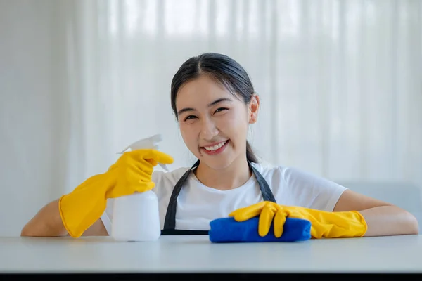 Asian women wear uniforms to prepare for housekeeping work, Wear an apron and rubber gloves to protect against cleaning chemicals, housekeeper is smiling happily before starting work, cleaning idea.