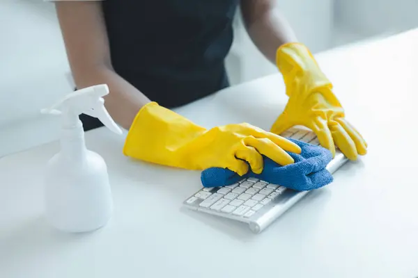Cleaning staff wiping down office equipment, Wipe the keyboard clean with a towel and disinfectant. Wear rubber gloves when working with cleaning chemicals, cleaning idea.