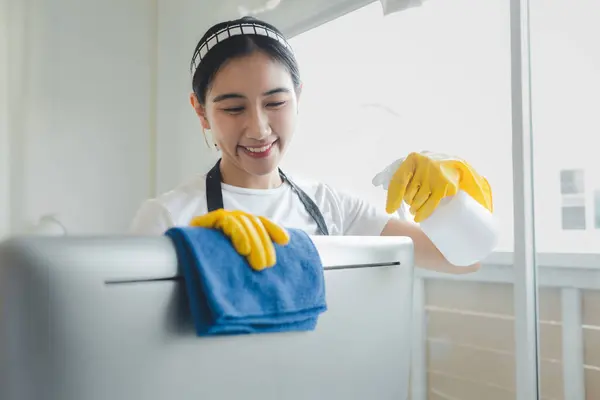 Asian female cleaner, Wear rubber gloves and an apron and work with a happy smile, Cleaning staff wiping down office equipment, Wipe the monitor clean with a towel and sanitizer, cleaning idea.