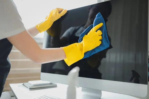 Cleaner is working, Wear rubber gloves and an apron to work, Cleaning staff wiping down office equipment, Wipe the monitor clean with a towel and sanitizer, cleaning idea.