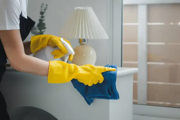 Housekeeper cleaning the furniture in the house, Wear an apron and rubber gloves to protect against cleaning chemicals, female wiping down tables with cleaning spray, cleaning idea.