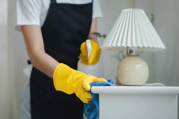 Housekeeper cleaning the furniture in the house, Wear an apron and rubber gloves to protect against cleaning chemicals, female wiping down tables with cleaning spray, cleaning idea.