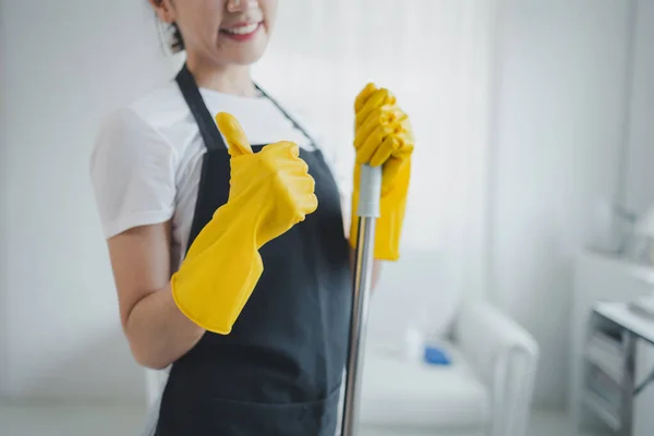 Asian women wear uniforms to prepare for housekeeping work, Wear an apron and rubber gloves to protect against cleaning chemicals, housekeeper is smiling happily before starting work, cleaning idea
