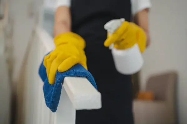 Housekeeper cleaning the furniture at home, Wear an apron and rubber gloves to protect against cleaning chemicals, female wiping down stairs with cleaning spray, cleaning idea.