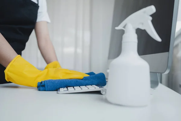 Cleaning staff wiping down office equipment, Wipe the keyboard clean with a towel and disinfectant. Wear rubber gloves when working with cleaning chemicals, cleaning idea.