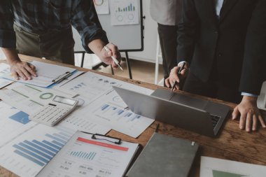 Gelirleri hesaplamak için birlikte çalışan bir grup işadamı, finansal rakamları gözden geçiriyorlar, finansal belgeleri çıkarıyorlar ve onları bir hesap makinesiyle, finansal fikirle kontrol ediyorlar..