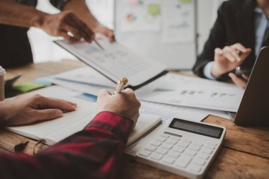 Gelirleri hesaplamak için birlikte çalışan bir grup işadamı, finansal rakamları gözden geçiriyorlar, finansal belgeleri çıkarıyorlar ve onları bir hesap makinesiyle, finansal fikirle kontrol ediyorlar..